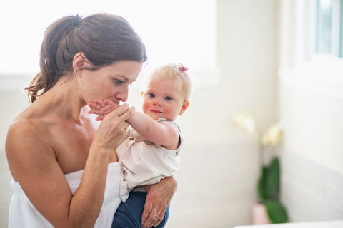 mom kissing babies hand, baby looking at camera