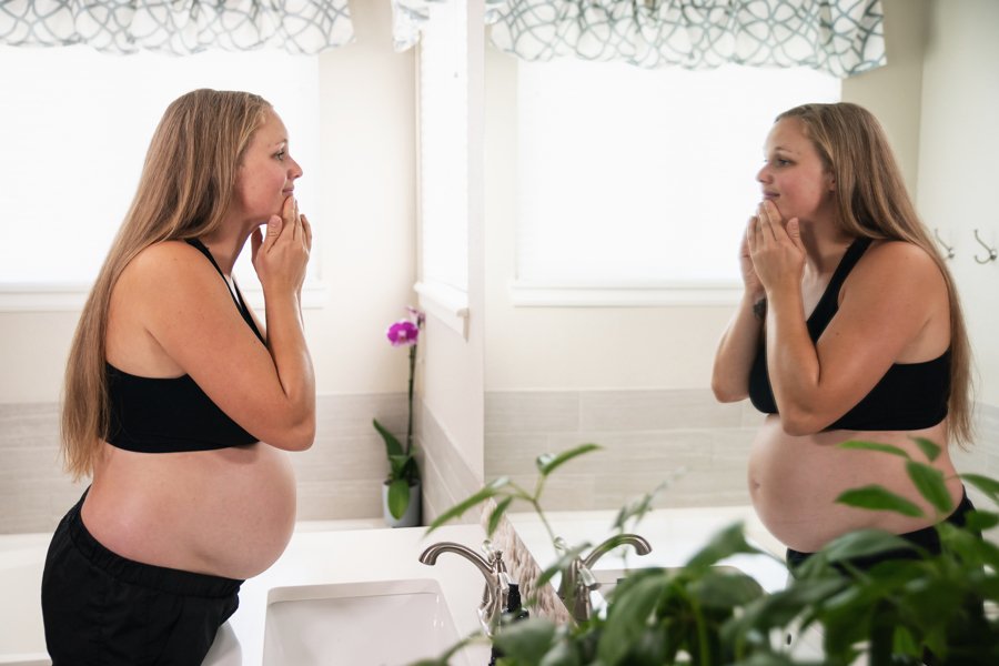 pregnant woman looing in mirror and smiling